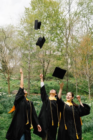 Graduates tossing caps in a park