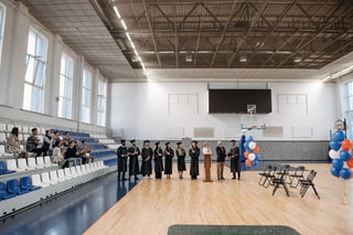 Graduation ceremony in a gymnasium with families watching