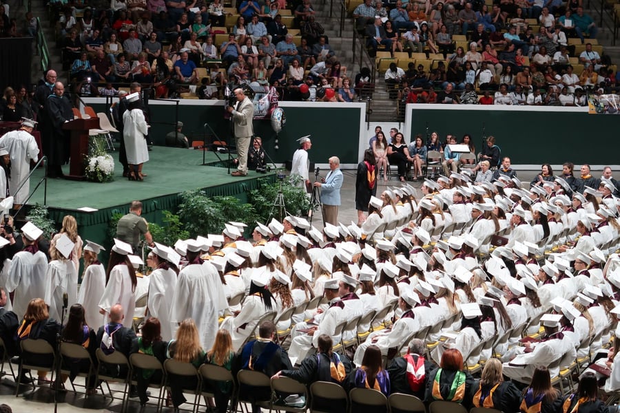 Graduates seated at a large indoor commencement