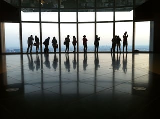 Row of guests silhouetted against a glass wall