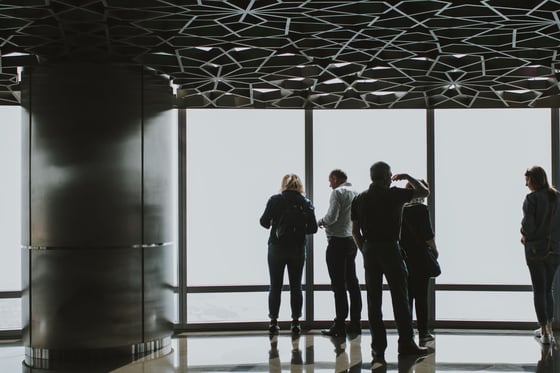Guests at an observation deck window with the view lost in fog