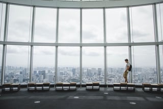 Visitor walking past panoramic windows above a city skyline