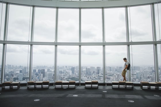 Visitor walking past panoramic windows above a city skyline