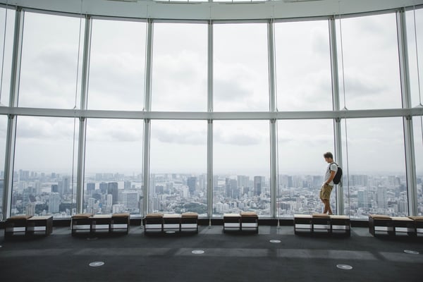 Visitor walking past panoramic windows above a city skyline