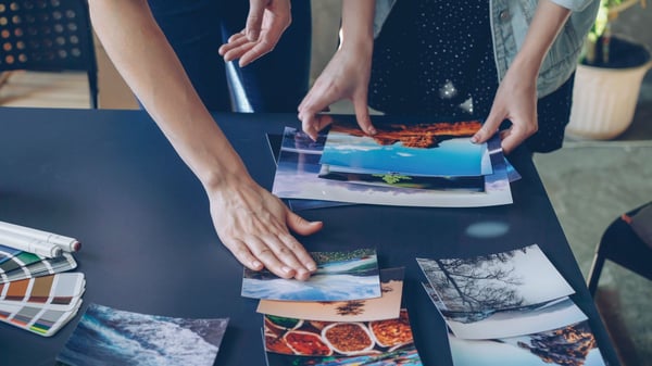Two people reviewing photo prints on a table