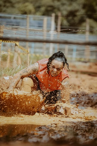 Participant crossing a muddy obstacle in a mud run