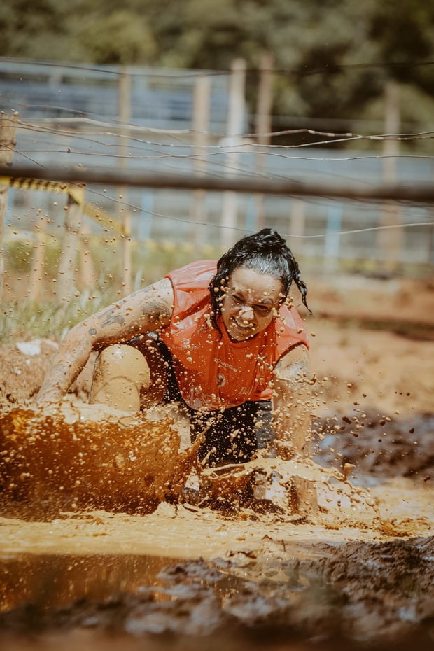 Participant crossing a muddy obstacle in a mud run