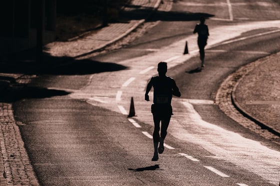 Runner silhouetted on a road during a race