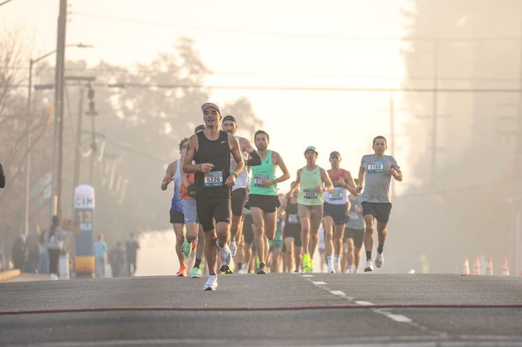Runners racing along a road on a foggy morning