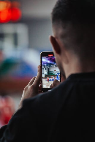 Fan filming a basketball game on a phone