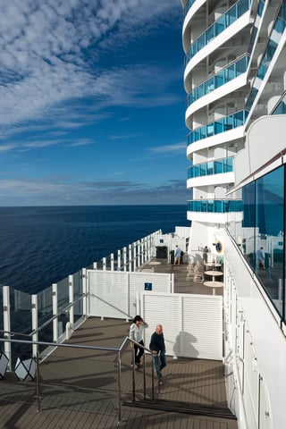 Guests on a cruise ship deck overlooking the ocean