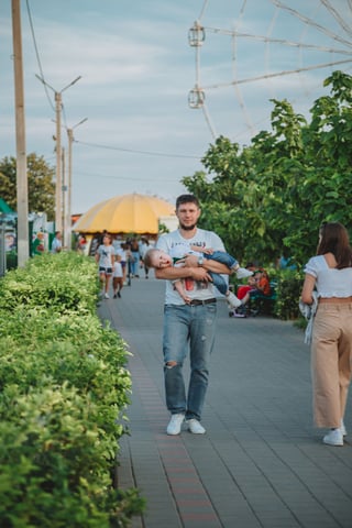 Father carrying his child through an amusement park