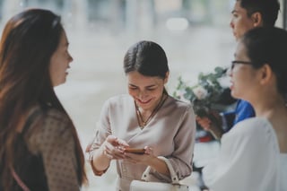 Wedding guest smiling at photos on her phone