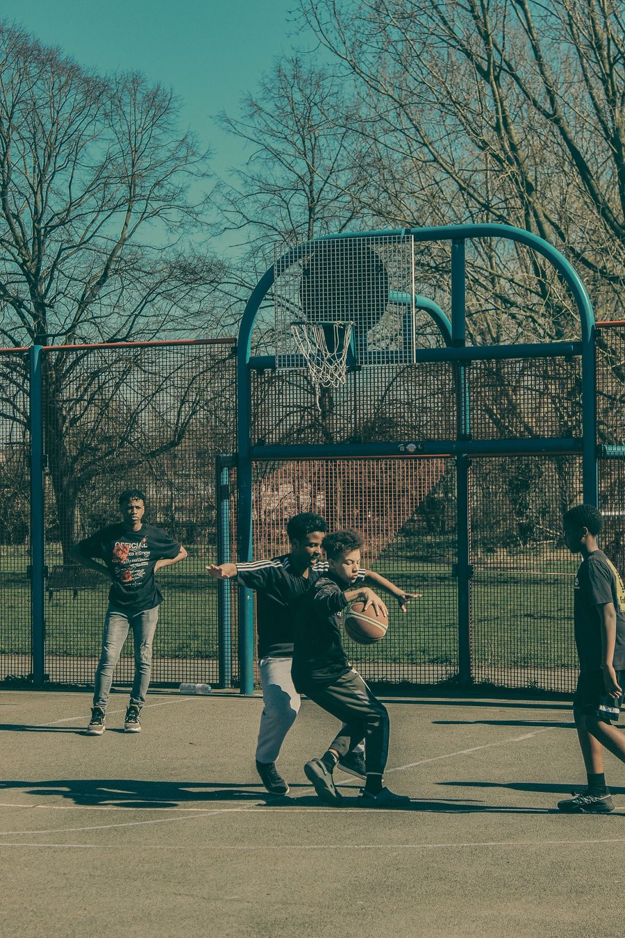 Teenagers playing basketball on an outdoor court