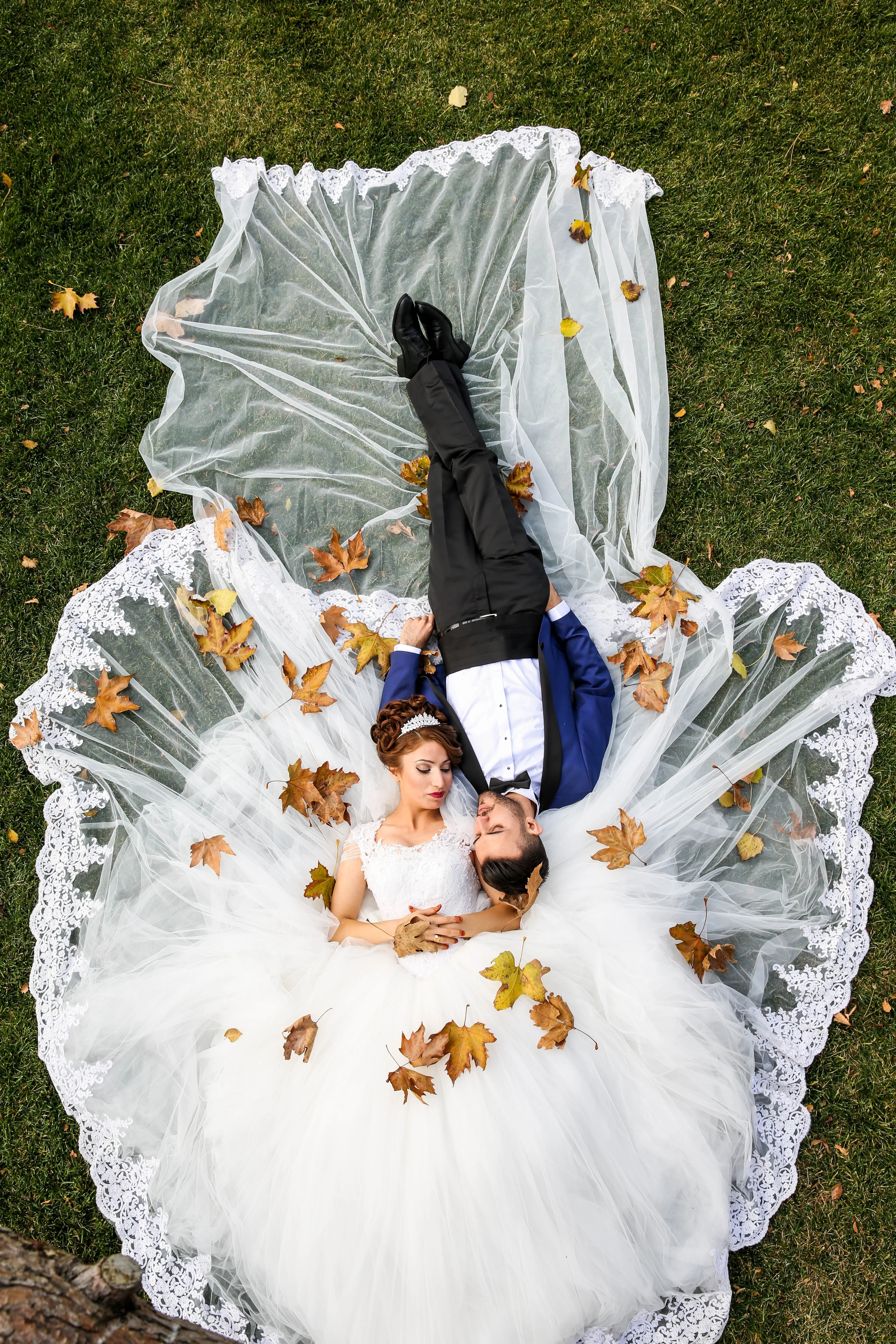 a wedding photograph of groom and bride lying on grass