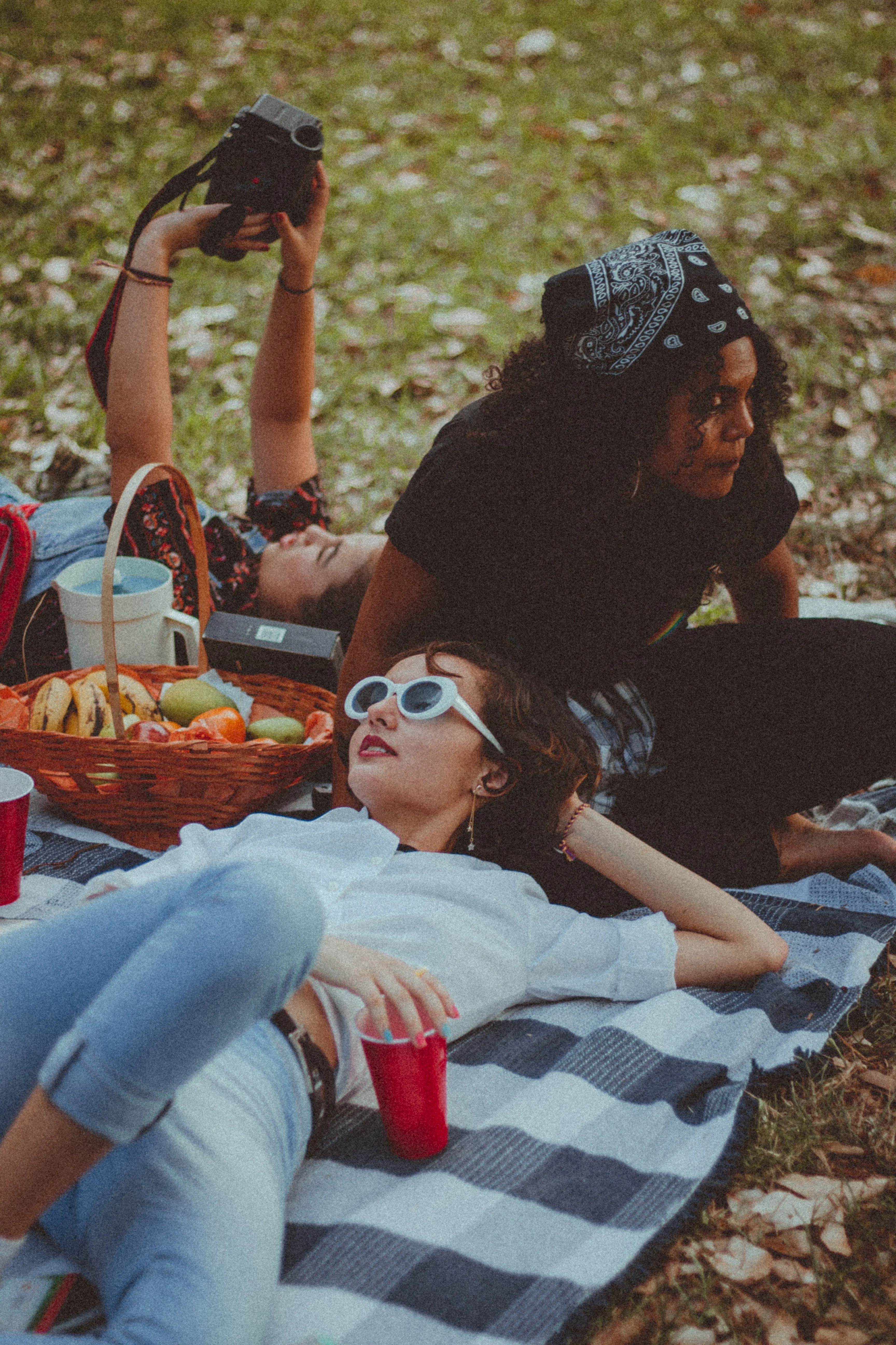 Three women sitting on a picnic blanket outdoors