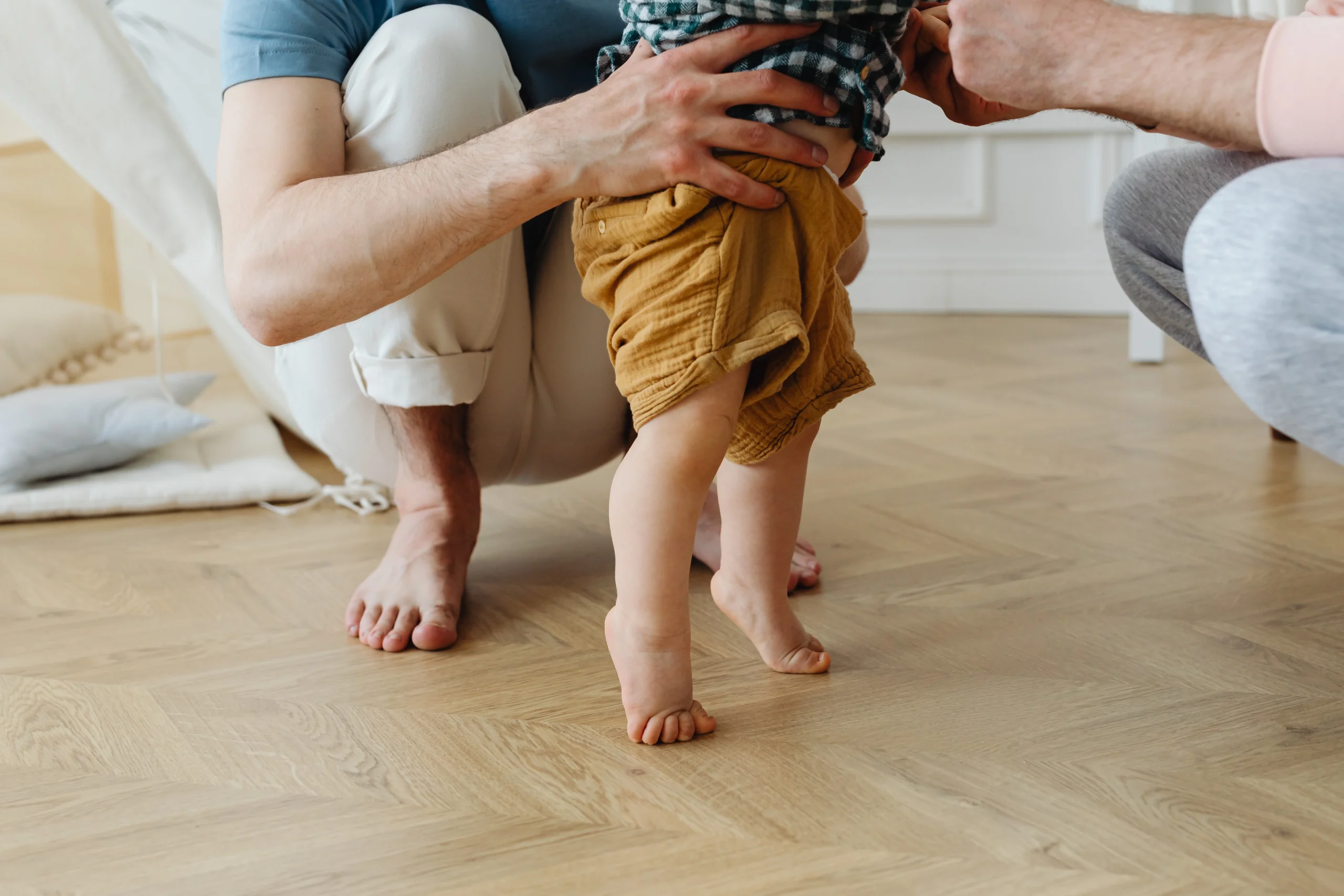photography of parents gently supporting a child as they learn to stand up