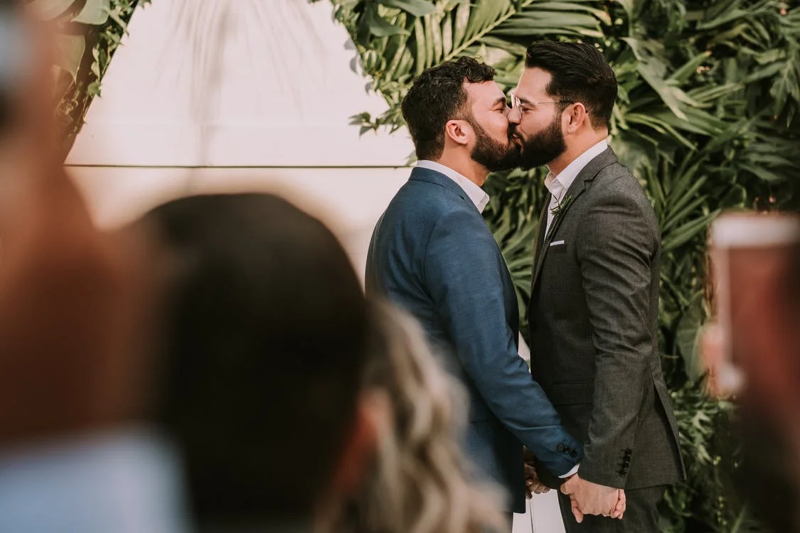 A wedding photograph of two men kissing