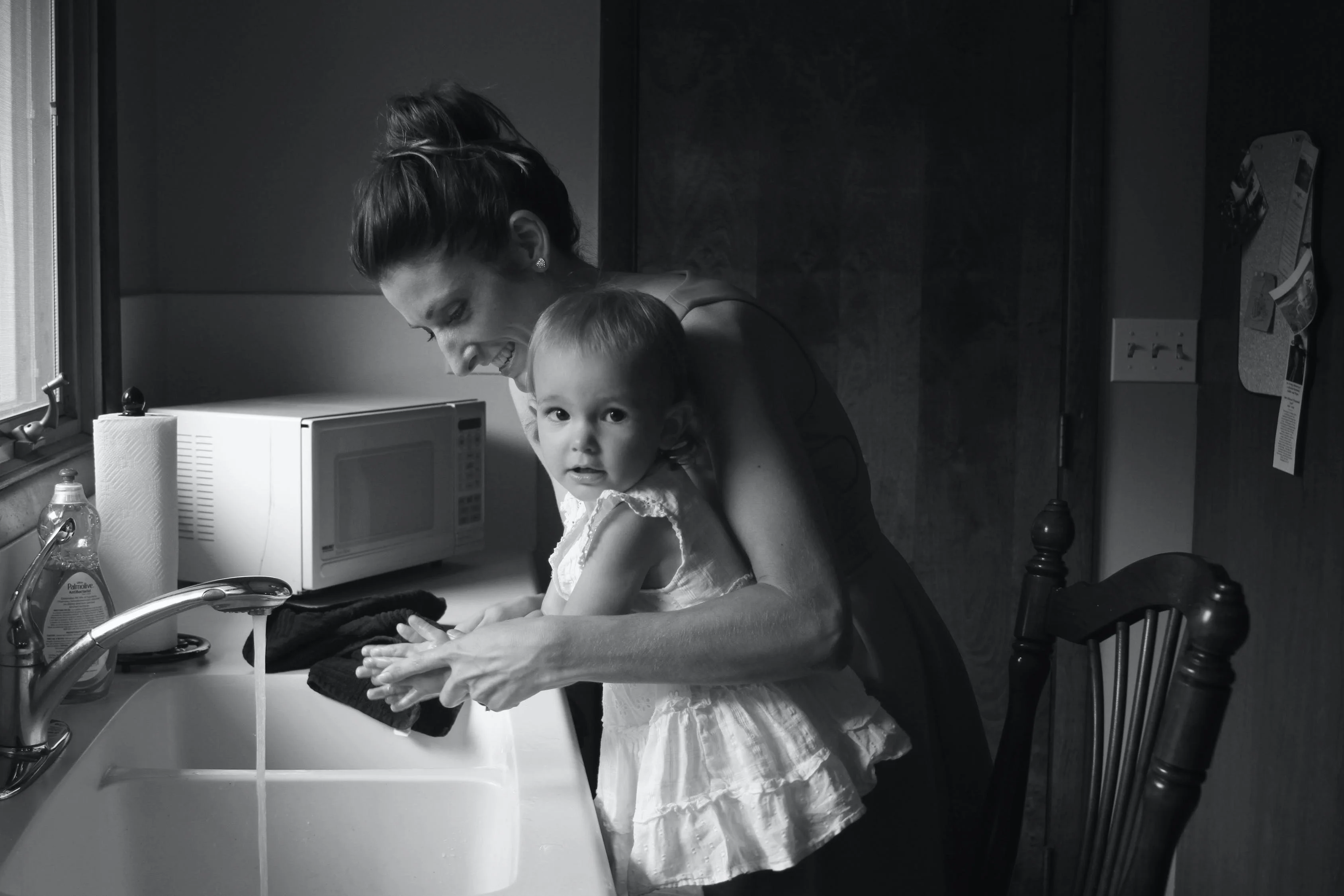 black and white family portrait of mother teaching daughter washing hands