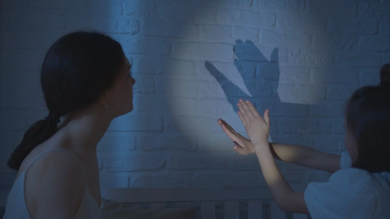 Photo of a mother and daughter creating shadow images with their hands